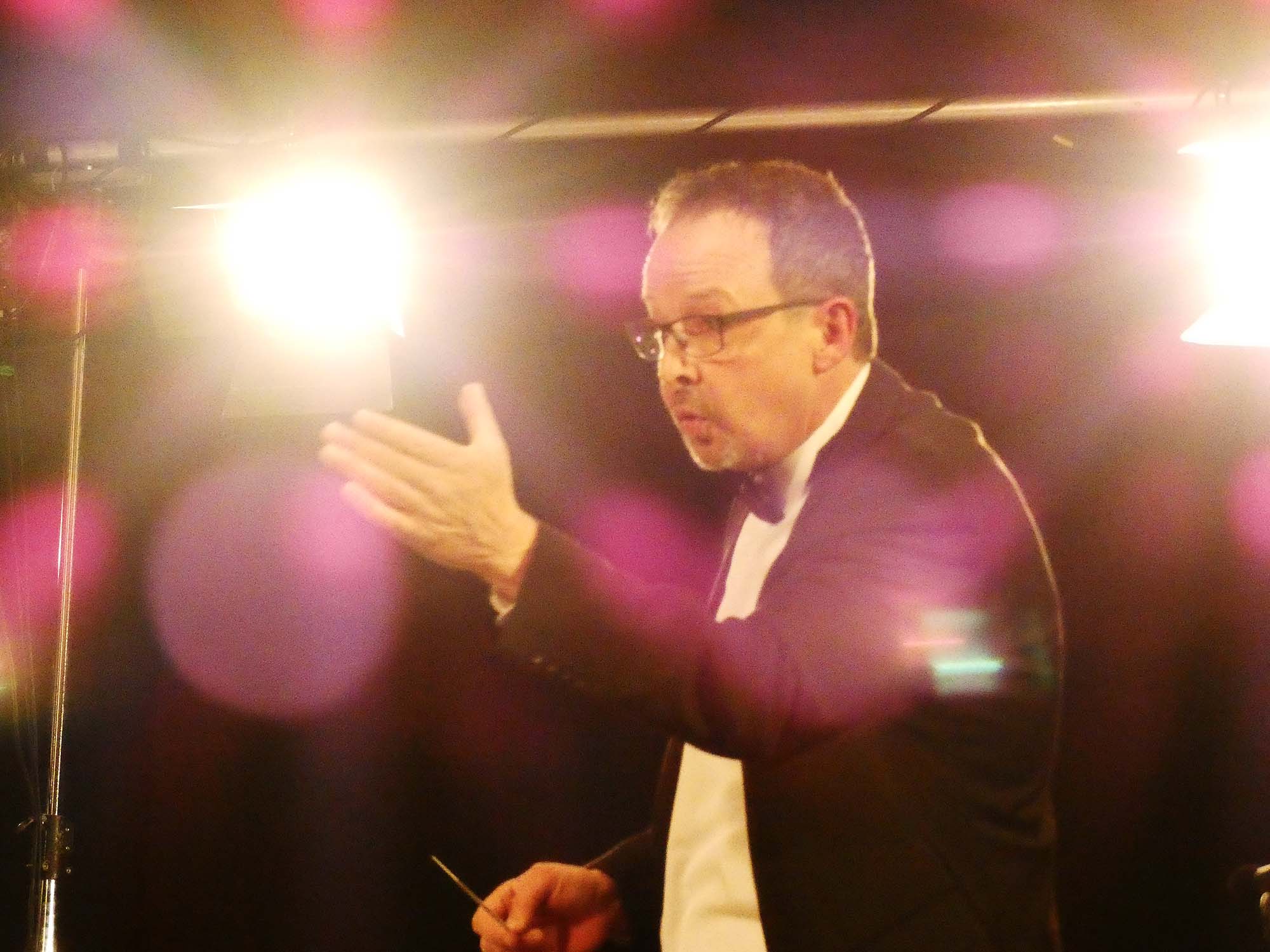 2023-3-27-BI-bia-Blasorchester-und-Dirigent inmitten von Lichtreflexen