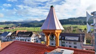 Das neue Glockentürmchen schwebt auf das sanierte Rathausdach
